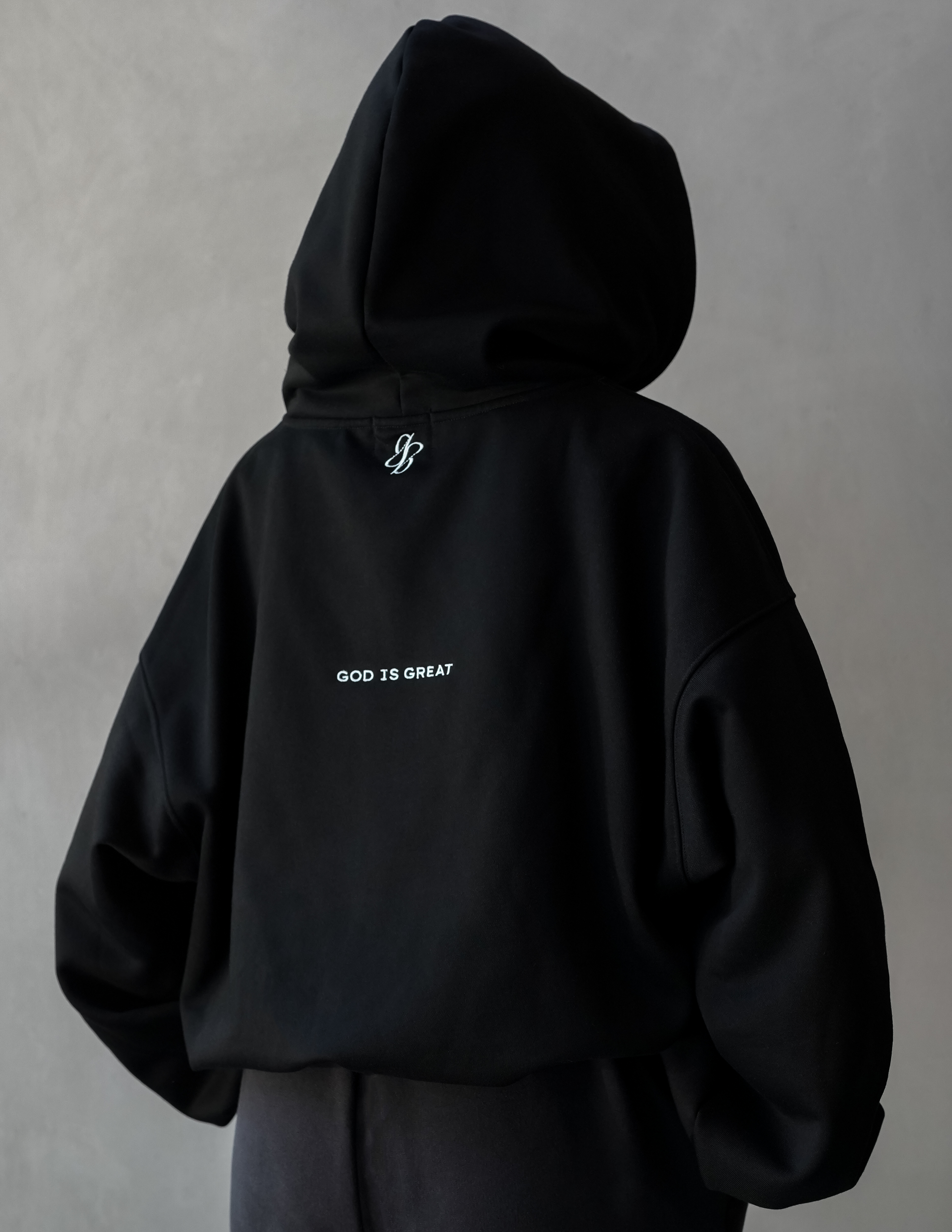 Black hoodie with 'GOD IS GREAT' text on a plain background