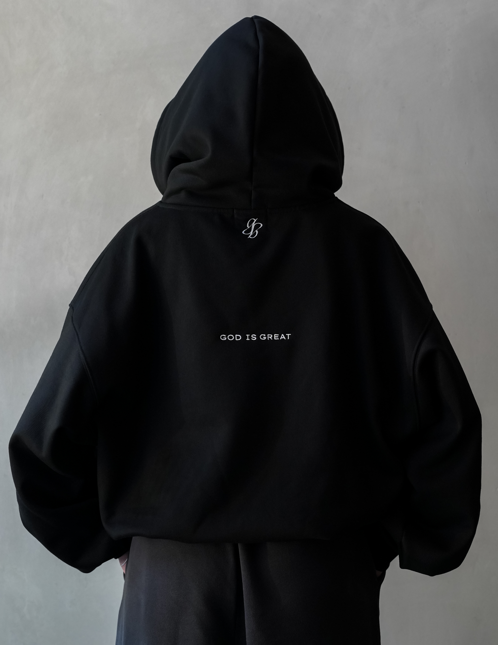 Black hoodie with 'GOD IS GREAT' text on a plain background