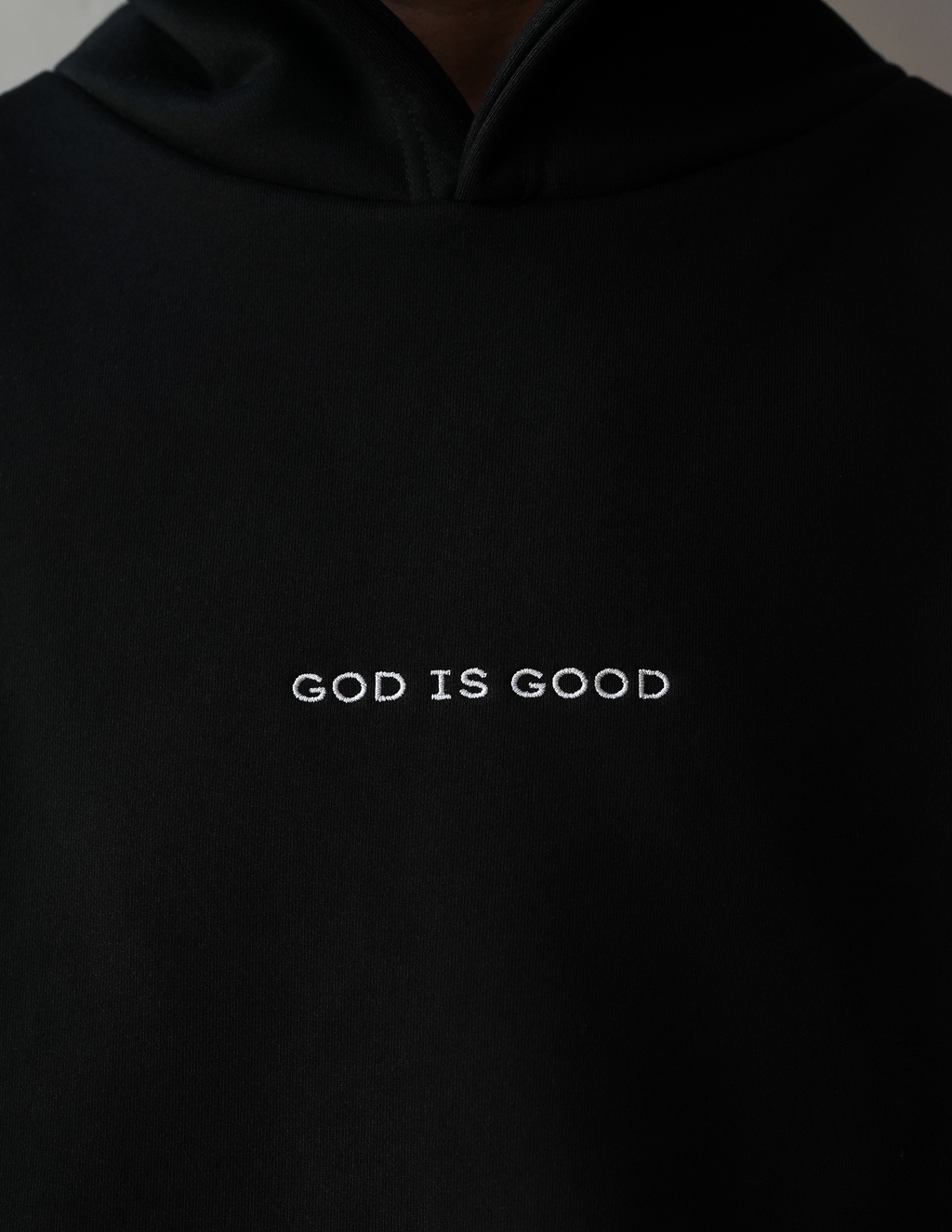 Black hoodie with 'GOD IS GOOD' text on a plain background