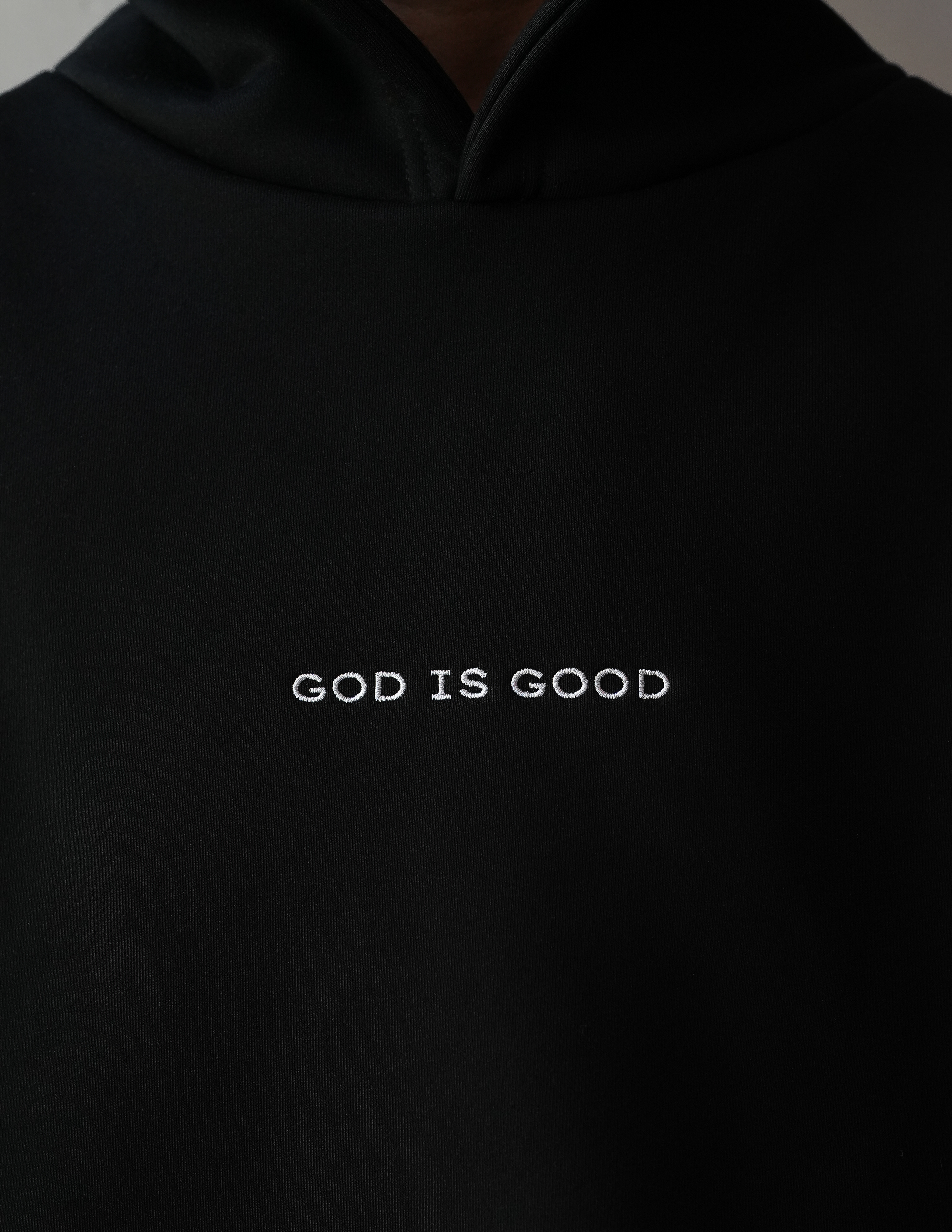 Black hoodie with 'GOD IS GOOD' text on a plain background